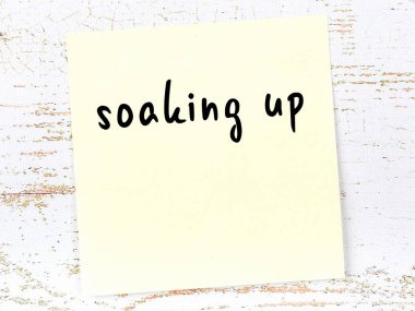 Tahta duvarda sarı yapışkan bir not ve el yazısıyla yazılmış bir yazı var.