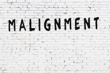 Beyaz tuğladan duvar, siyah boyayla yazılmış kötü yazı.