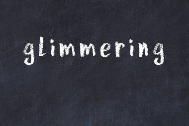 Tebeşir el yazısıyla yazılmış yazı siyah masada parlıyor.