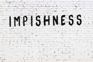 Beyaz tuğlalı duvar. Siyah boyayla yazılmış.