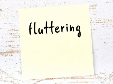 Kanat çırpmayla ilgili hatırlatma kavramı. Tahta duvarda üzerinde yazı olan sarı yapışkan kağıt.