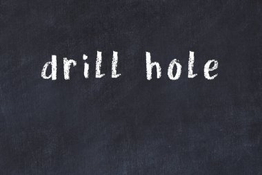 Tebeşir elle yazılmış matkap deliği siyah masanın üzerinde.