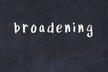 Tebeşir el yazısıyla yazması siyah masanın üzerinde genişliyor