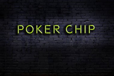 Duvara yazılı bir poker çipi olan neon levhası. Gece görünümü