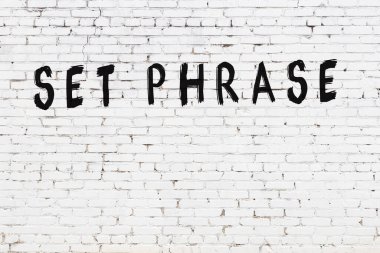 Beyaz tuğla duvara siyah boya ile yazılmış bir yazı dizisi..