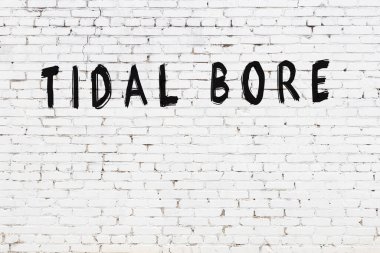 Üzerinde yazı olan beyaz tuğla duvar siyah boyayla el yazısıyla kaplanmış.