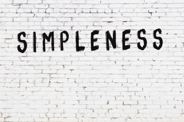 Yazı basitliği beyaz tuğla duvara siyah boya ile yazılmış..