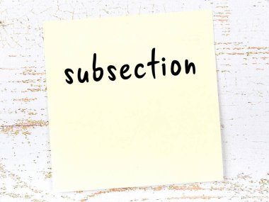 Tahta duvardaki sarı yapışkan notta elle yazılmış altyazı var.