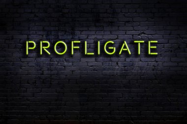 Üzerinde yazı olan neon levhası tuğla duvara karşı savurgan. Gece görünümü