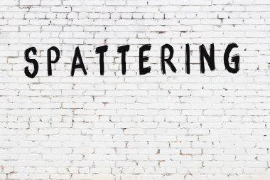 Yazı, beyaz tuğla duvara siyah boya ile yazılmış..