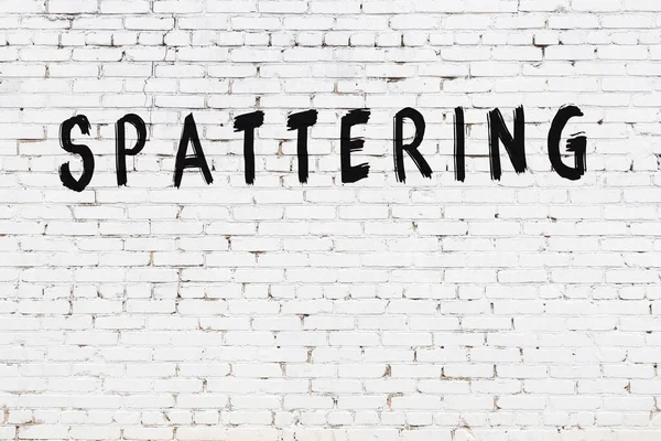 Yazı, beyaz tuğla duvara siyah boya ile yazılmış..