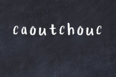 Tebeşir el yazısıyla yazılmış kaoutchouc yazısıyla siyah masaya yazılmış.