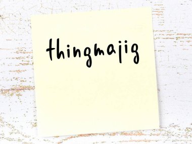 Ahşap duvarda sarı yapışkan bir not ve el yazısıyla yazılmış bir şey.