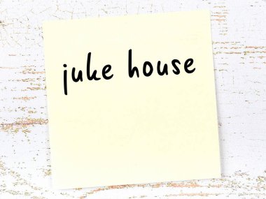 Tahta duvarda el yazısıyla yazılmış bir müzik evi olan sarı yapışkan bir not.