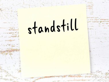 Tahta duvarda el yazısıyla yazılmış sarı yapışkan bir not var.