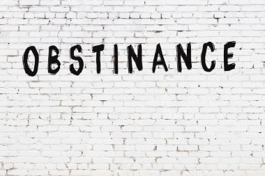 Beyaz tuğlalı duvar. Siyah boyayla yazılmış.