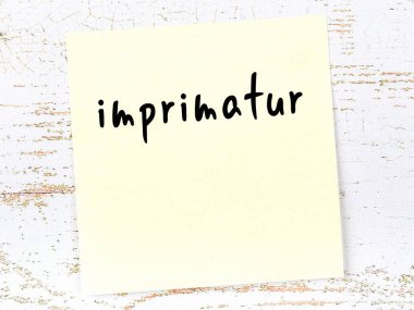 Tahta duvarda el yazısıyla yazılmış sarı yapışkan bir not var.