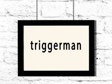 Siyah ahşap çerçeve ve beyaz tuğla duvarda asılı duran tetikçi. 