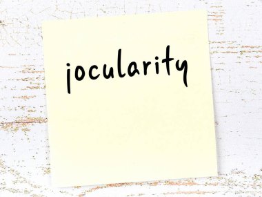 Tahta duvardaki sarı yapışkan notta el yazısıyla yazılmış sevinç yazısı var.