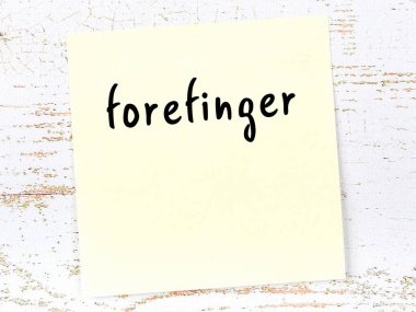 Tahta duvarda el yazısıyla yazılmış işaret parmağı olan sarı yapışkan bir not.