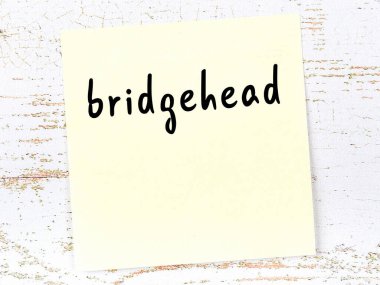 Tahta duvarda el yazısıyla yazılmış bir köprü başı olan sarı yapışkan bir not.