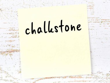 Tahta duvardaki sarı yapışkan notta el yazısıyla yazılmış tebeşir taşı var.