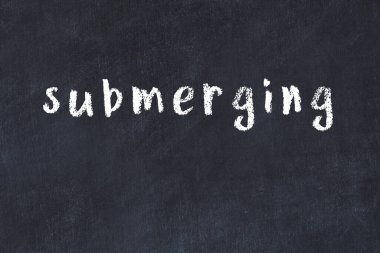 Tebeşir elle yazılmış yazıtlar siyah masanın üzerine gömülüdür.