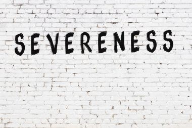 Beyaz tuğlalı duvar. Üzerinde yazı var. Şiddeti siyah boyayla yazılmış.