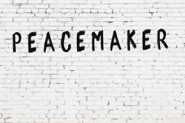 Beyaz tuğla duvara siyah boya ile yazılmış bir yazıcı..