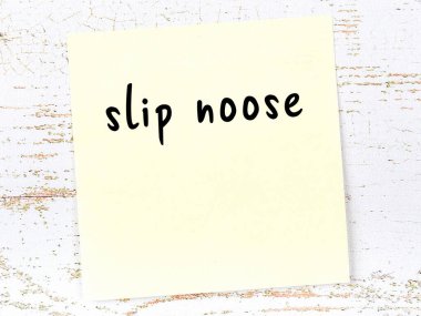 Tahta duvardaki sarı yapışkan notta el yazısıyla yazılmış bir ilmik var.