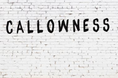 Beyaz tuğlalı duvar. Üzerinde yazı var. El yazısı siyah boya.