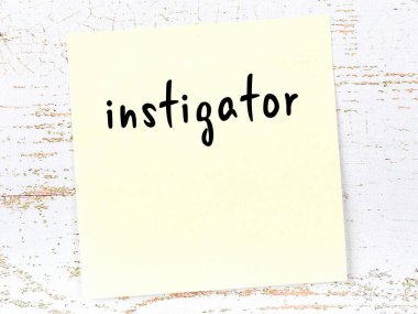 Tahta duvardaki sarı yapışkan notta elle yazılmış kışkırtıcı yazılar var.