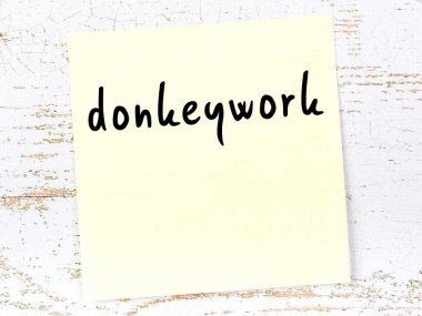 Ahşap duvardaki sarı yapışkan notta el yazısıyla yazılmış eşek işi var.