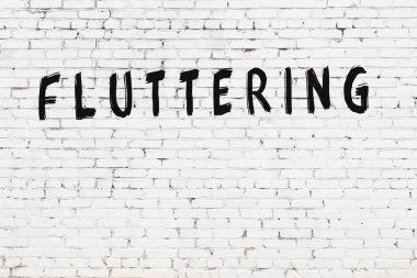 Yazılı beyaz tuğla duvar, el yazısıyla siyah boya ile çırpınıyor.