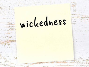 Kötülük hakkında hatırlatma kavramı. Tahta duvarda üzerinde yazı olan sarı yapışkan kağıt.