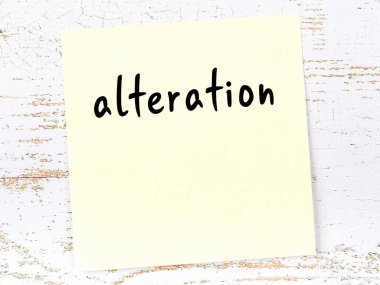 Tahta duvardaki sarı yapışkan notta el yazısıyla yazılmış yazması değiştirilmiş.