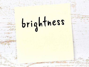 Parlaklık hakkında hatırlatma kavramı. Tahta duvarda üzerinde yazı olan sarı yapışkan kağıt.