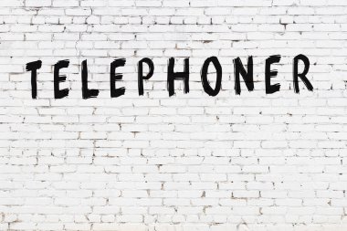 Üzerinde yazı olan beyaz tuğla duvar. Siyah boyalı el yazısıyla telefon.