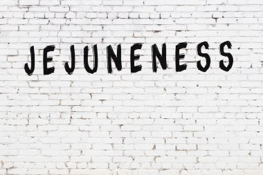 Beyaz tuğlalı duvar, siyah boyayla yazılmış.