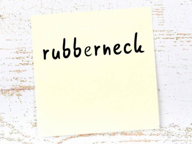 Ruberneck 'i hatırlatma kavramı. Tahta duvarda üzerinde yazı olan sarı yapışkan kağıt.
