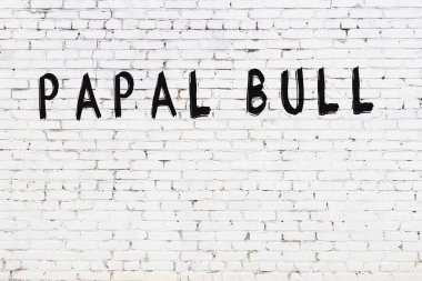 Beyaz tuğlalı duvar. Üzerinde papalık boğası yazılı. Üzerinde siyah boya var.