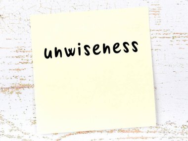 Tahta duvardaki sarı yapışkan notta el yazısıyla yazılmış akılsızlık var.