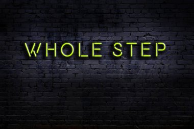 Üzerinde yazı olan neon levhası tuğla duvara karşı bir adım. Gece görünümü