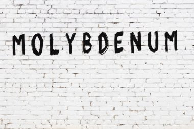 Beyaz tuğla duvara siyah boya ile yazılmış molibdenum yazımı.
