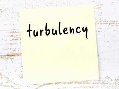 Tahta duvarda el yazısıyla yazılmış türbülans içeren sarı yapışkan bir not.
