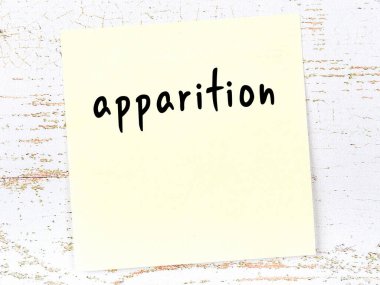 Tahta duvarda el yazısıyla yazılmış sarı yapışkan bir not var.