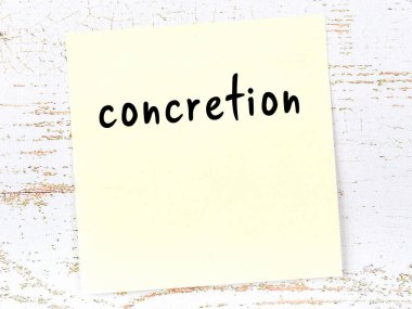 Tahta duvardaki sarı yapışkan notta elle yazılmış somut yazı var.