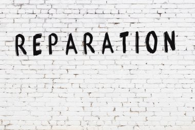 Yazı tazminatı beyaz tuğla duvarda siyah boyayla yazılmış..