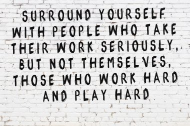 Beyaz tuğla duvara zekice alıntılar yazılı siyah bir yazı.