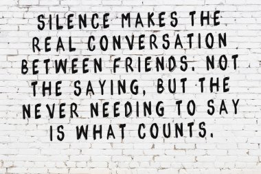 Beyaz tuğla duvara zekice alıntılar yazılı siyah bir yazı.